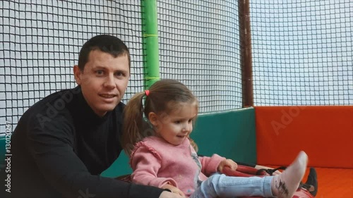 the little girl on the tubing rolls with slides in the play area. Dad and daughter smiling and looking at the camera