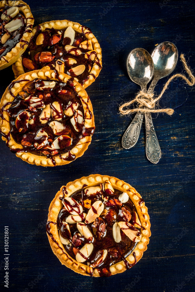 Mini tarts with nuts and caramel on a rustic background, top view, copy space Mini tarts with nuts and caramel on a rustic background, top view, copy space