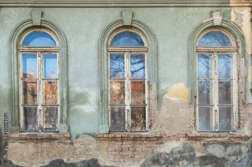 three dilapidated windows on the old hobbled home