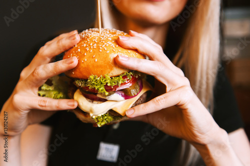 beautiful young, healthy girl holds a tasty big burger with beef cutlet