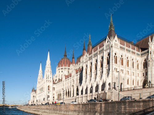 Daytime view of historical building of Hungarian Parliament, aka Orszaghaz, with typical symmetrical architecture and central dome on Danube River embankment in Budapest, Hungary, Europe. It is
