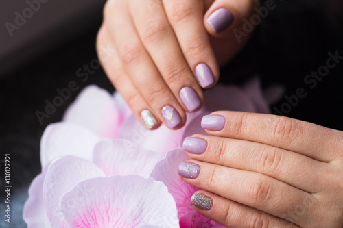 Hand with manicured nails on a pink background flowers