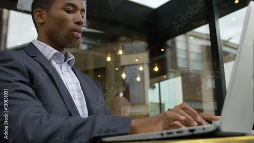 Wallpaper Mural black elegant businessman working with his laptop sitting in a cafe in the city  Torontodigital.ca