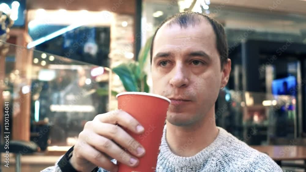 Thoughtful man having big disposable paper cup of coffee in a cafe. 4K video Thoughtful man having big disposable paper cup of coffee in a cafe. 4K video