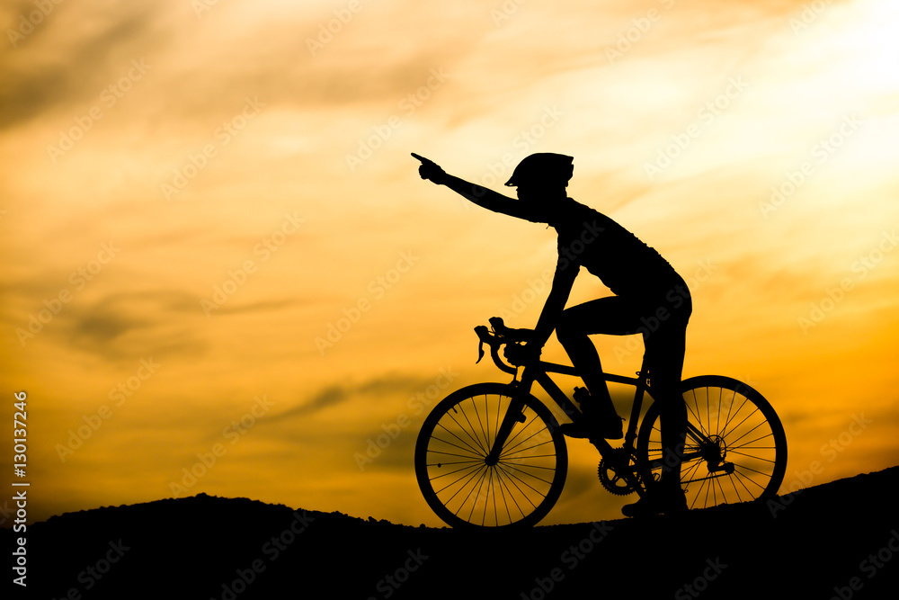Obraz premium Silhouette of man with bicycle at sunset