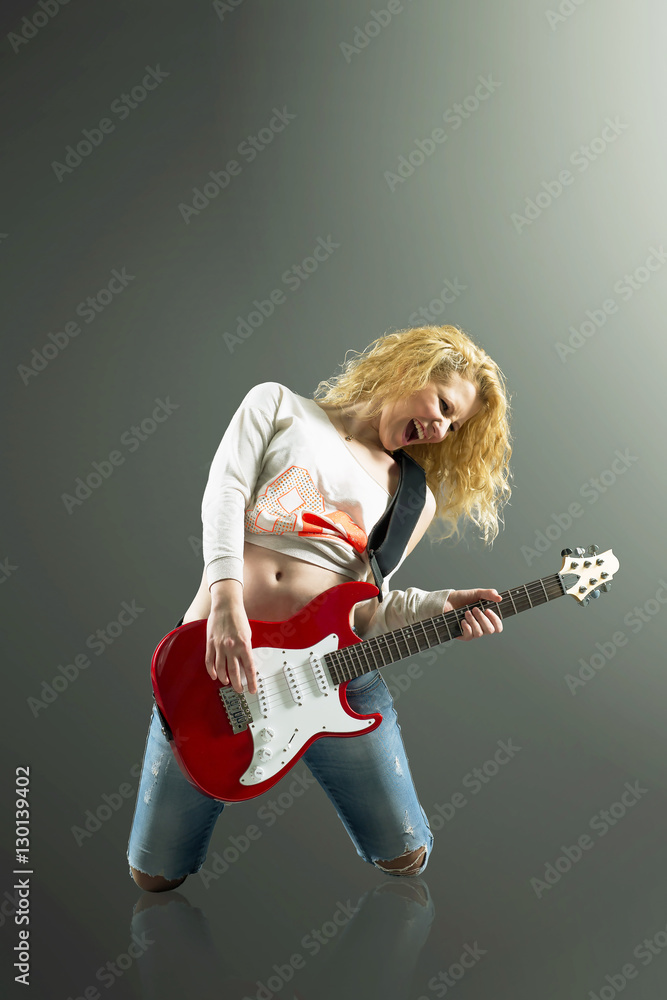 beautiful young blonde woman with a guitar sings a rock song