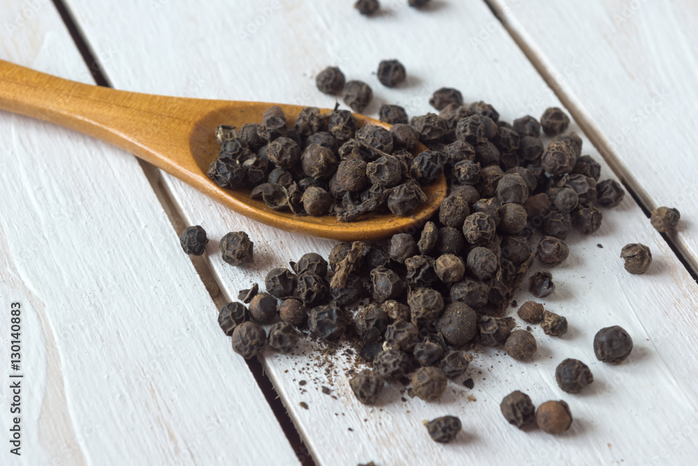 Closeup view of black pepper corns and spoon on white wooden background
Closeup view of black pepper corns and spoon on white wooden background