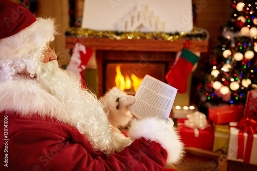 Santa Claus sitting and reading children wishes for x-mas.