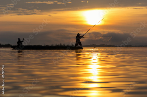 Silhouette of asia traditional fisherman in action when fishing