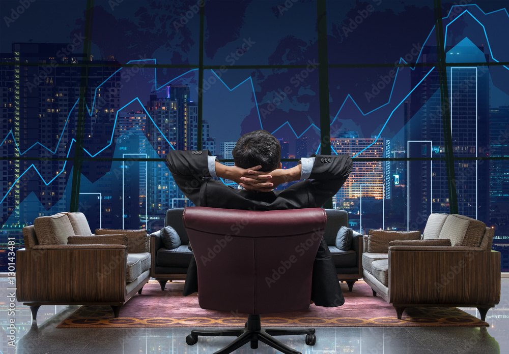 Back side of sitting businessman who is looking at Trading graph