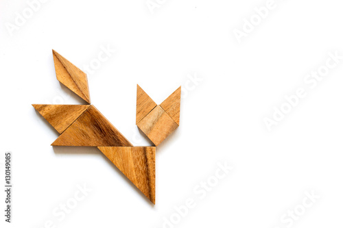 Wooden tangram as running cat shape on white background