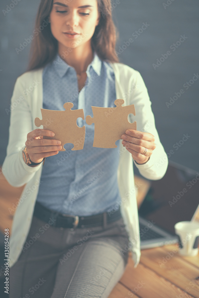 Business woman holding and pointing to a puzzle piece Business woman holding and pointing to a puzzle piece
