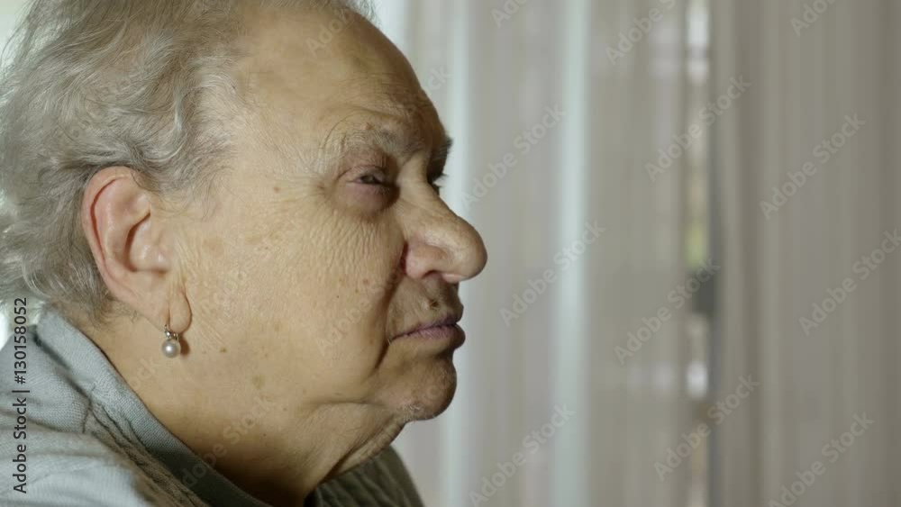 family matriarch alone at home, sitting on a chair recalling her old times family matriarch alone at home, sitting on a chair recalling her old times