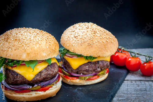 Homemade beef burgers on a black slate background.