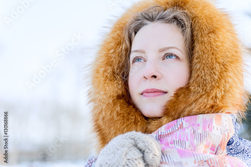 outdoor winter portrait of a beautiful girl in the hood with fur