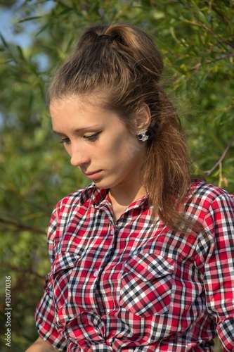 Young brunette girl in the red shirt is very sad and thinks