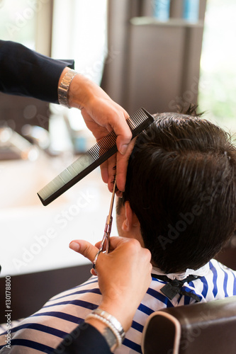 Barber cutting customer's hair with a pair of scissors