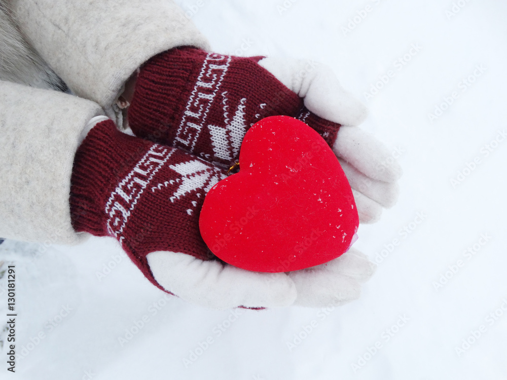 woman hands in mittens with red heart on snow
