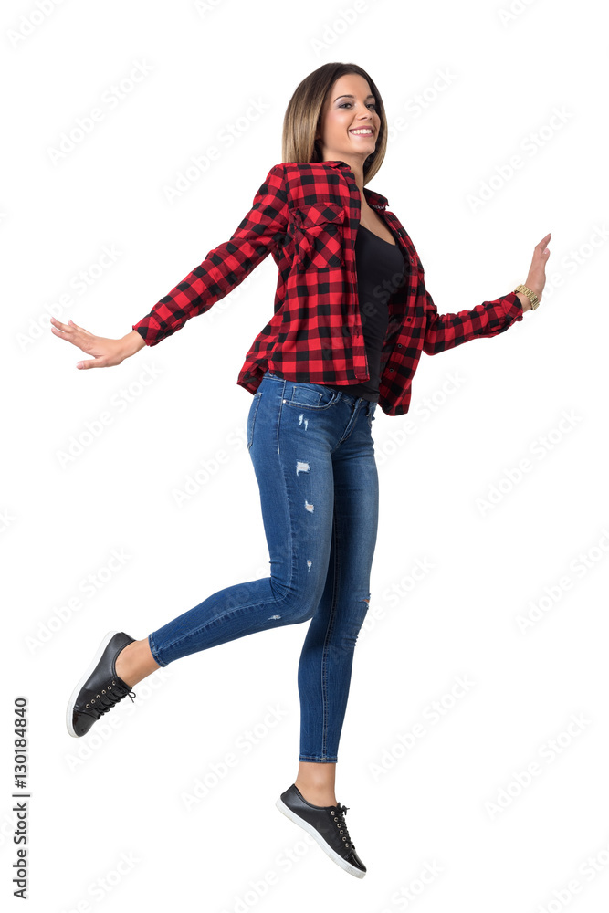 Carefree young cheerful woman in jeans and red plaid shirt jumping in mid air. Full body length standing portrait isolated over white background. Carefree young cheerful woman in jeans and red plaid shirt jumping in mid air. Full body length standing portrait isolated over white background.