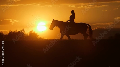 Woman riding horse on field during sunset