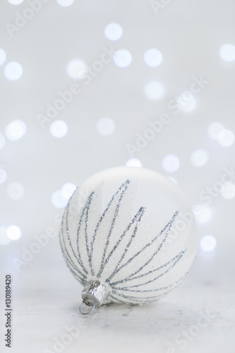 Christmas scene with one white and silver ball and christmas bokeh lights in background