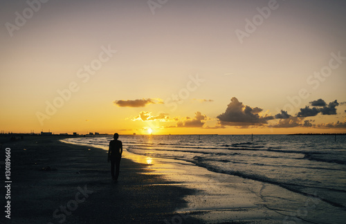 lonely man walking on the beach at sunset..