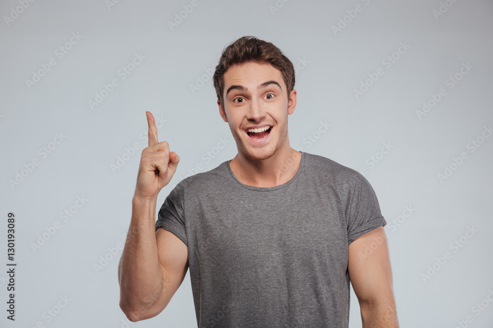Excited happy man pointing finger up at copyspace Excited happy man pointing finger up at copyspace