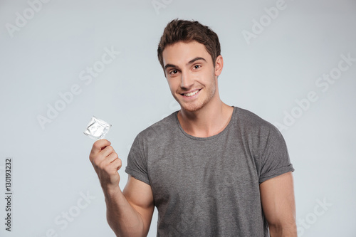 Portrait of a smiling casual man holding condom