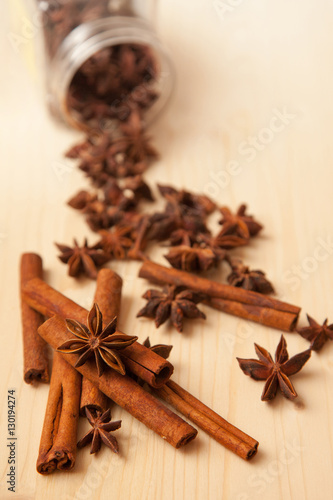 seasoning cinnamon (Cinnamomum) and anise (Anisium vulgare Gaerto) lies on a light wood surface, spilled from a jar, close-up, background, healthy lifestyle