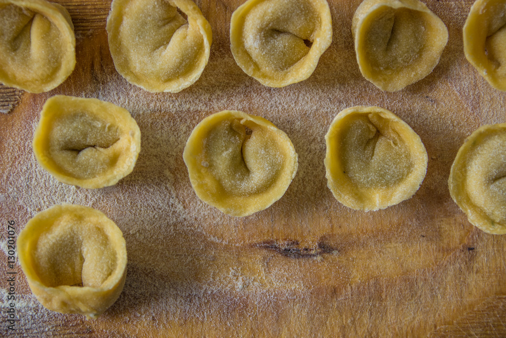 Freshly prepared Italian tortellini on wooden board top view Freshly prepared Italian tortellini on wooden board top view