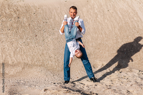 stylish father walking on the sand with his son a summer day