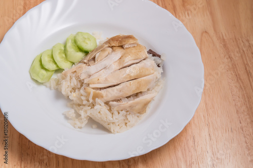 Sliced Hainan-style chicken with marinated rice in white dish on wooden plate,This Thai food is called Khao Man Kai .