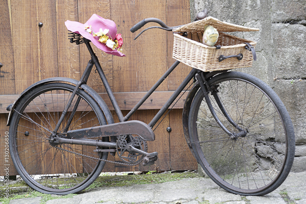 Old bicycle with a basket and a pink straw hat
