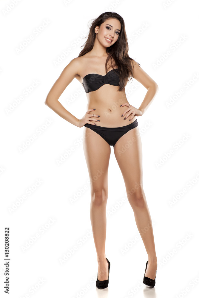 young girl in black bikini posing on a white background young girl in black bikini posing on a white background