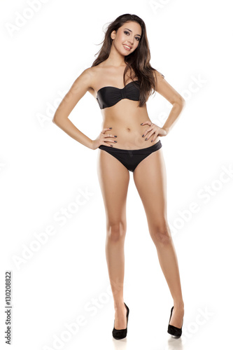 young girl in black bikini posing on a white background © vladimirfloyd