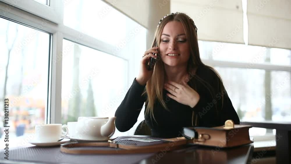 The woman emotionally speaks by phone in a cafe