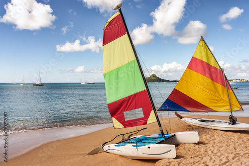 Fotografie Colorful sail boat and catamaran rest on sandy beach
