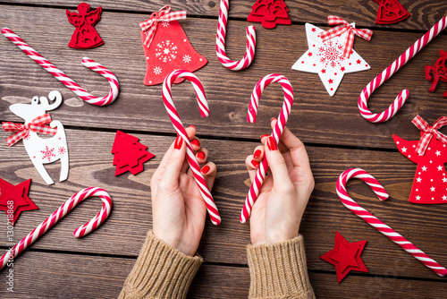 Woman holding candy cane over wooden table. Christmas background. photo