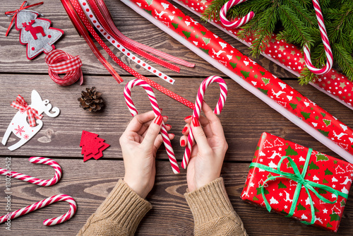 Woman holding candy cane over wooden table. Christmas preparations concept.