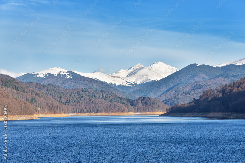 Mountain lake panorama against cloudy sky and mountains covered