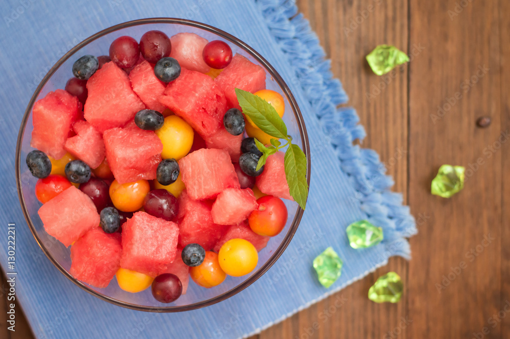 Fruit and berry salad of watermelon, blueberries, plums, currants, gooseberry, cherry plum. Wooden background. Top view. Close-up