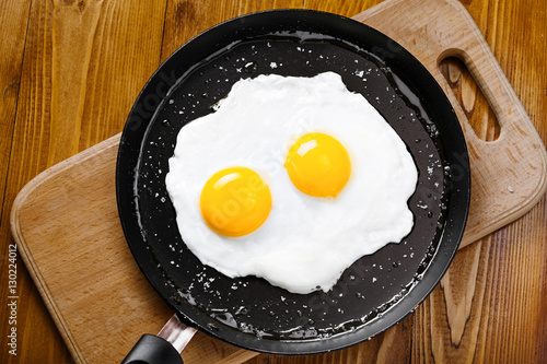 Fried eggs meal in a frying pan for delicious healthy breakfast. Traditional international breakfast food, top view.