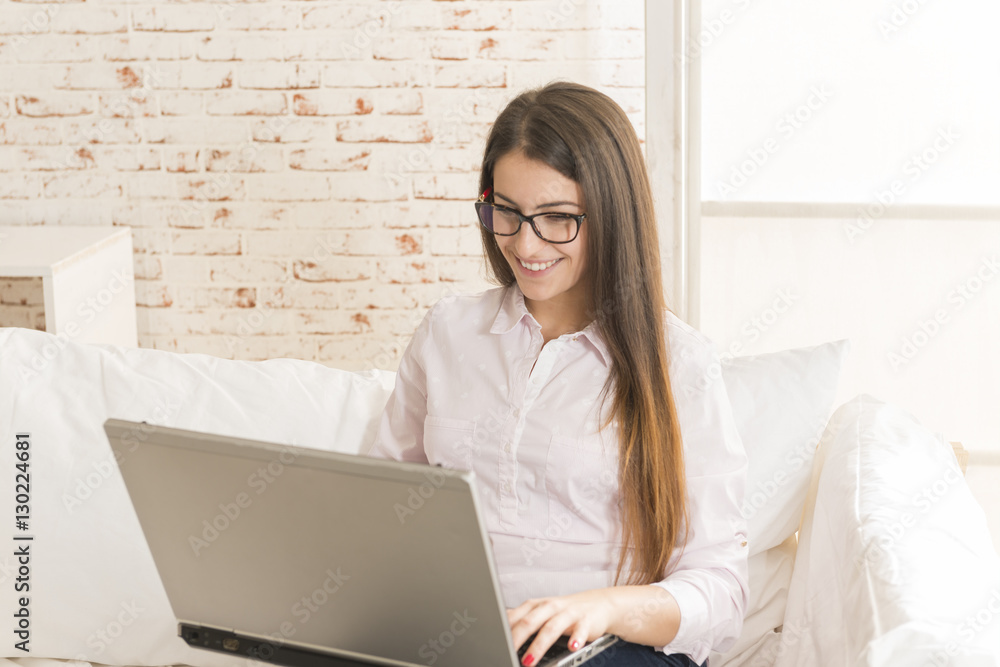 Happy young woman sitting on the sofa typing on laptop. Work from home. Online study. Happy young woman sitting on the sofa typing on laptop. Work from home. Online study.