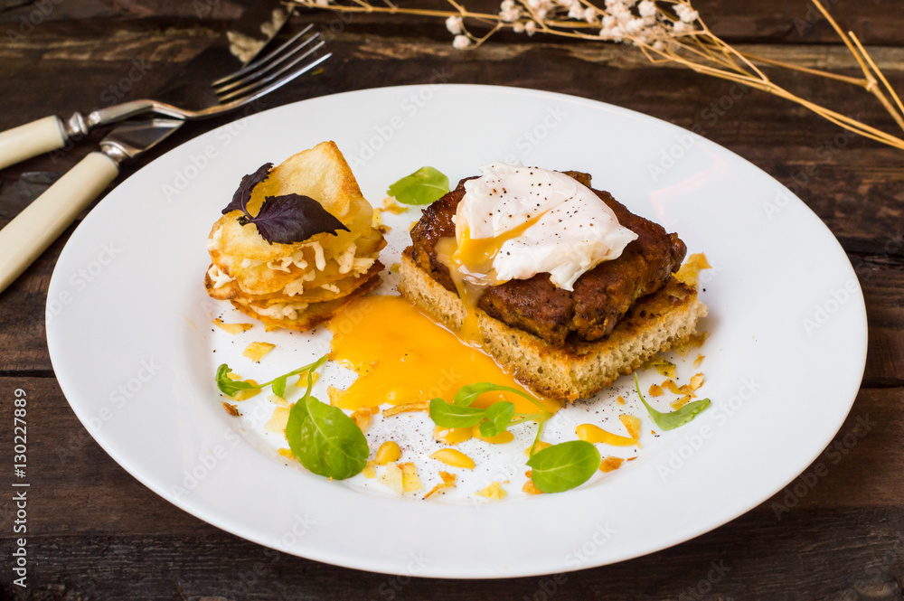 Dish with meat steak on toast, potato chips  melted cheese and poached egg  Dutch sauce. Wooden background. Top view. Close-up