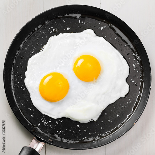 Traditional healthy easy quick breakfast meal made of two fried eggs served on a frying pan. International simple food, top view.