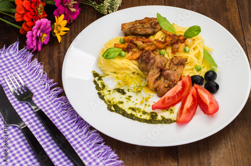 Tagliolini with meat in tomato sauce, olives and   spinach. Wooden background. Close-up. Top view