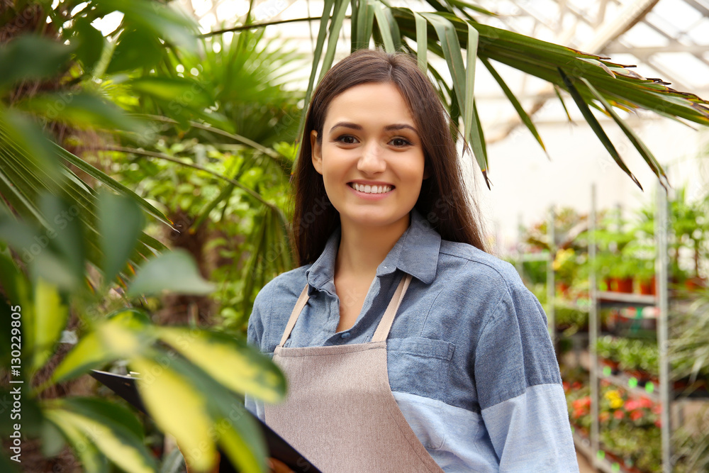 Pretty young florist with clipboard in greenhouse Pretty young florist with clipboard in greenhouse