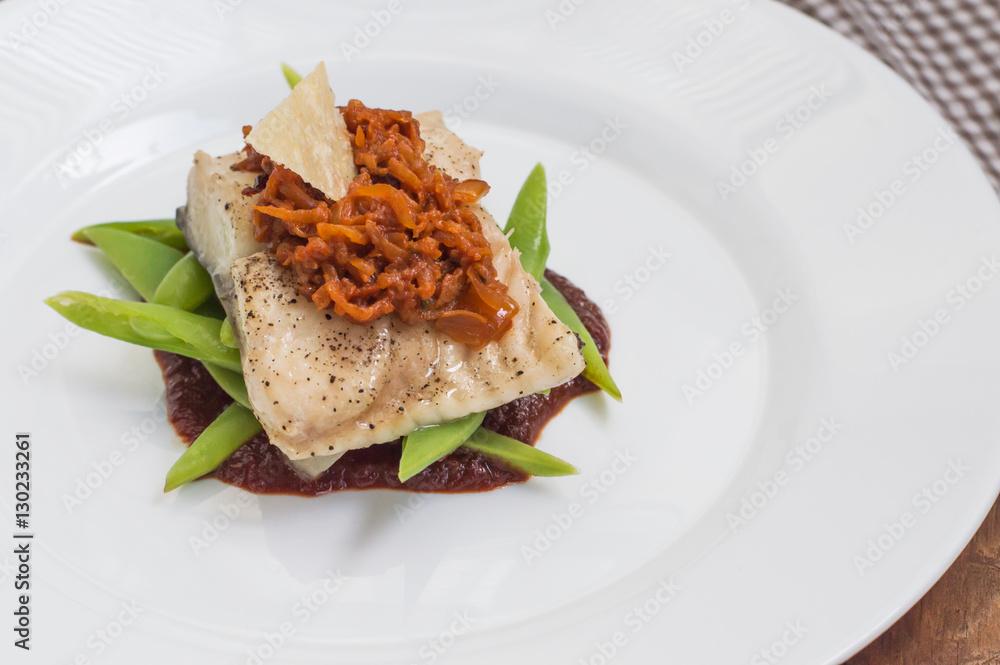 Cooked fish with steamed asparagus, vegetable ragout, tomato sauce and potato chips. Wooden background. Top view. Close-up