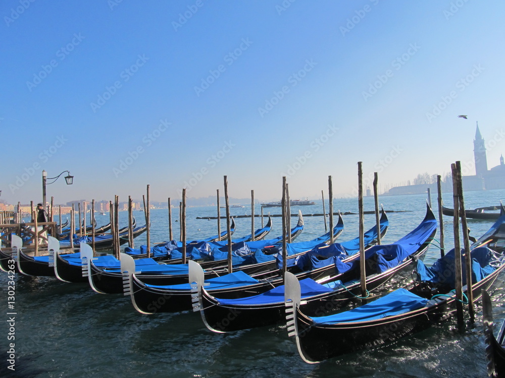 Number of blue gondolas on a blue background of water and sky