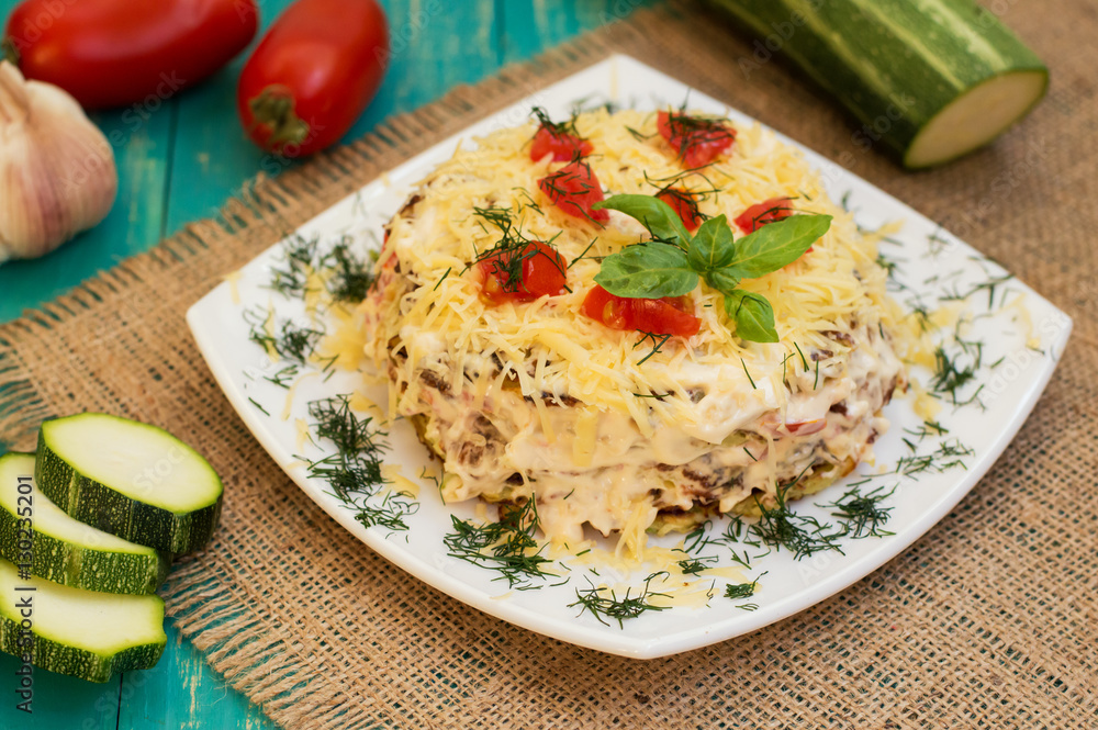 The cake of zucchini with cheese, tomato and basil. Wooden background. Close-up The cake of zucchini with cheese, tomato and basil. Wooden background. Close-up
